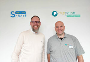 Die beiden Geschäftsführer Ralf Rottmann (Ärzte-Dienst Scharf GmbH & Co.KG) und Alexander Herms (Pflegefreunde) lächeln in die Kamera