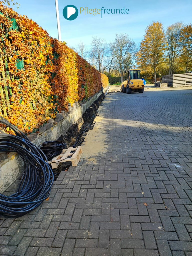 Ein Teil des Parkplatzes. Außen ist der Boden aufgerissen und das Verlegen der dort liegenden Kabel ist sichtbar