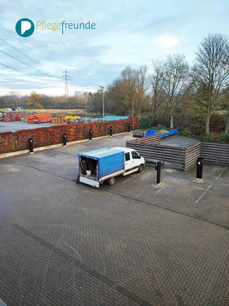Parkplatz von oben. Alle Ladesäulen sind zu sehen sowie ein blauer Transporter. Hinten rechts ein Container