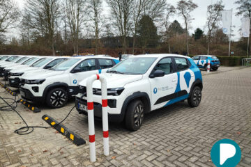 Parkplatz voll mit den E-Autos. Im Vordergrund sind zwei Autos mit blauer Folierung im Pflegefreunde-Design zu sehen.