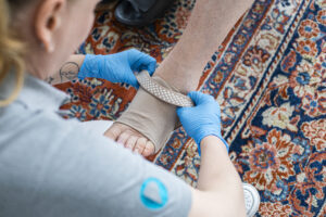 Pflegekraft zieht dem Patienten einen Kompressionstrumpf an