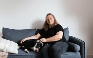 Mareike sitzt mit Hund Fips auf einer grauen Couch