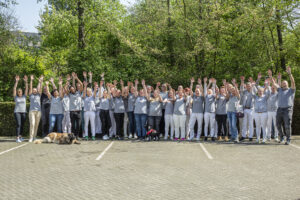 Das ganze Team der Pflegefreunde steht draußen und jubelt. Halten die Hände hoch