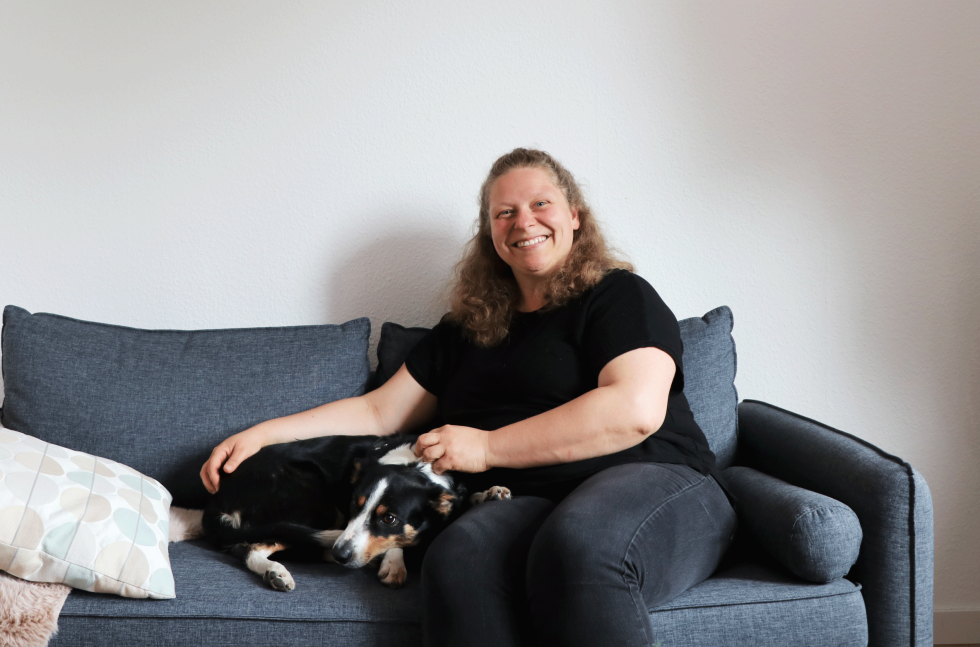 Mareike sitzt mit Hund Fips auf einer grauen Couch