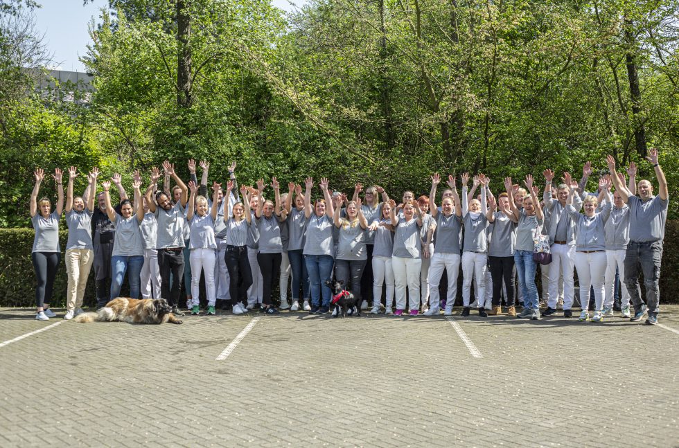 Das ganze Team der Pflegefreunde steht draußen und jubelt. Halten die Hände hoch